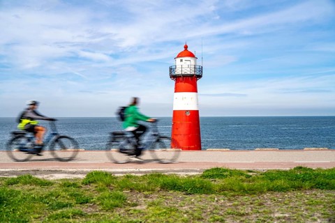 North Sea dyke near Westkapelle, Westkapelle Laag lighthouse, cyclists on the Zeeuwse Wind Route