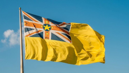 The flag of Niue, an island state in the Pacific Ocean, flutters in the wind, isolated against a