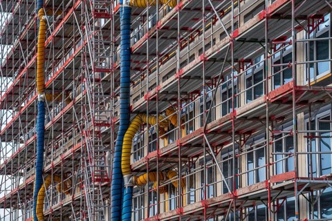 Large construction site, scaffolded shell of an office building complex, air hoses for building