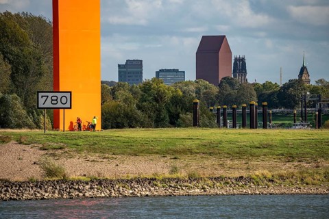 The sculpture Rhine Orange at the mouth of the Ruhr into the Rhine, skyline of the city centre of
