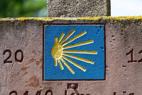 Stone slab with blue shell, showing pilgrims on the Way of St James the way to Santiago de