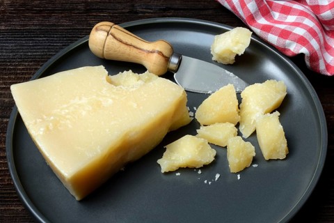 A piece of Parmesan cheese and chopped pieces of cheese on a plate