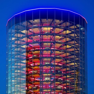 An illuminated car tower with new cars for delivery in the evening, Autostadt, Volkswagen AG,