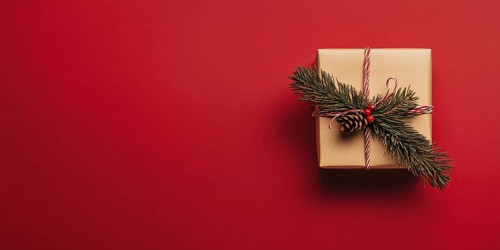 Banner with small Christmas gift box wrapped in graft paper on red background with copy space.