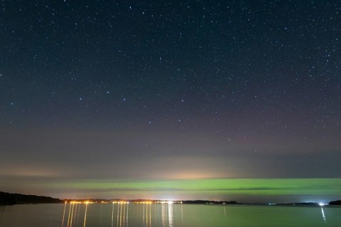 Northern lights (aurora borealis) shine on a starry night over Lake Plau, Ganzlin,