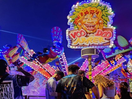 People in front of the illuminated carousel Voodoo Jumper at night, Cranger Kirmes, Herne, Ruhr
