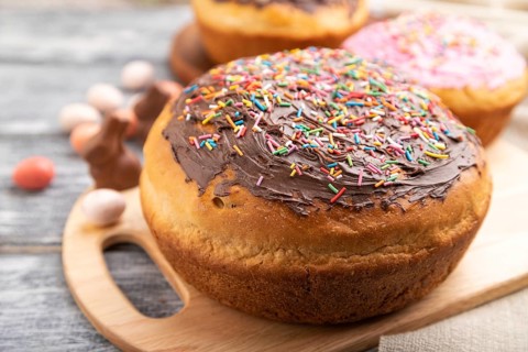 Homemade glazed and decorated easter pies with chocolate eggs and rabbits on a gray wooden