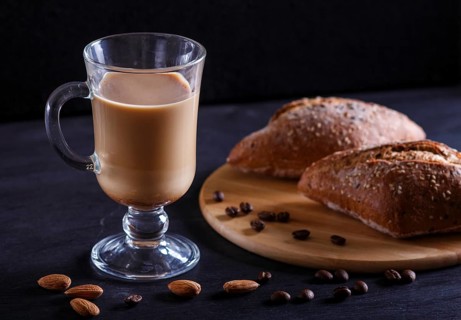 Glass cup of coffee with cream and buns on a black background. close up