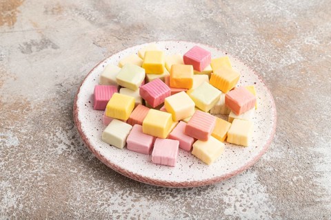 Various fruit jelly chewing candies on plate on brown concrete background. apple, banana,