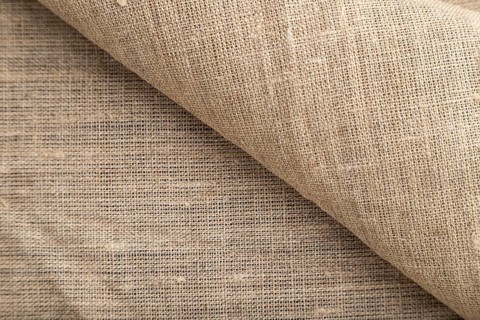 Fragment of rough linen tissue. Side view, natural textile background and texture