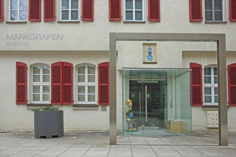 House wall with shutters and entrance to the Margrave Museum, window, glass wall, inscription,