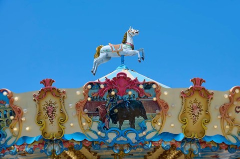 Colourfully decorated carousel with horse decoration under a clear blue sky, summer,