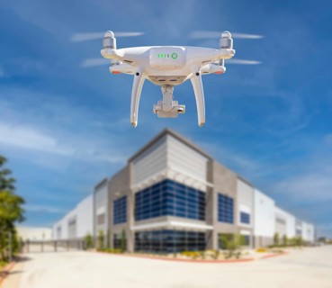 Unmanned aircraft system (UAS) quadcopter drone in the air near corporate building