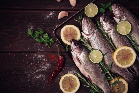 Raw rainbow trout, with lemon and herbs, on a wooden table, no people