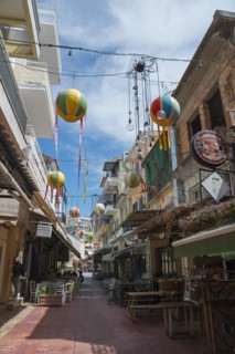 Narrow alley decorated with colourful hanging balloons, surrounded by shops, Kalamata, Messinia,