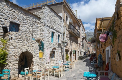 Cosy alley with stone houses and a alleyway café in a small Mediterranean town on a sunny day, Old