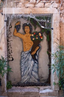 A mural of Bacchus surrounded by plants on an old stone wall, Umag, Istria, Croatia, Europe