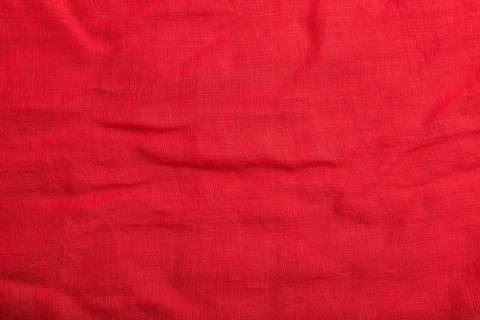 Fragment of smooth red linen tissue. Top view, flat lay, natural textile background and texture