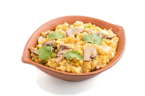 Lentils porridge with champignons and coriander in a clay bowl isolated on white background. Side