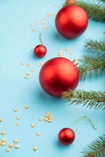 Christmas or New Year composition. Decorations, red balls, fir and spruce branches, on a blue paper