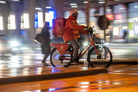 Street at the main station, Lieferando courier, cyclist, rainy weather, city centre, in the