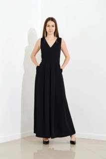 Beautiful stylish woman dressed in long sleeveless dress posing over bright wall. The image