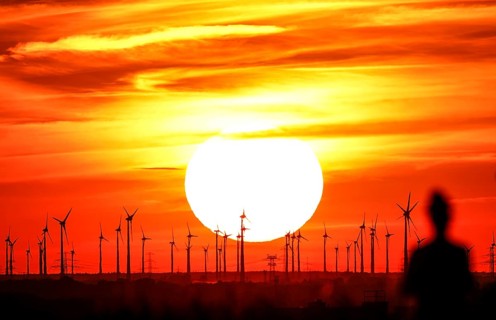 Joggers on Berlin's Drachenberg at sunset. A wind farm near Nauen in Brandenburg can be seen in the