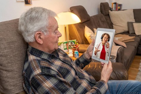 Symbolic image of telemedicine, elderly patient speaking to a doctor in a video conference from