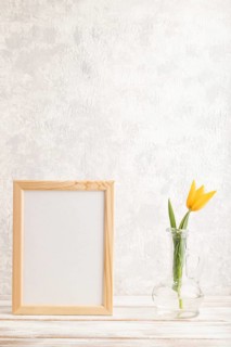 Wooden frame with orange tulip flower in glass on gray concrete background. side view, copy space,