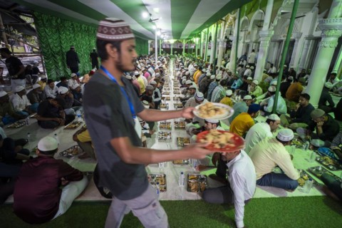 Volunteers distribute and arrange rows of 'iftar' meal for devotees to break their fast, during the
