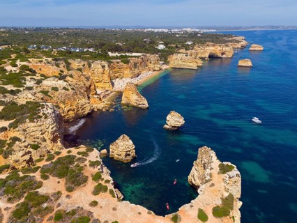 Aerial view of a rugged coastal landscape with rocky islands and boats in turquoise water, beach,