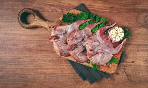 Raw quail meat, on a cutting board, with spices and herbs, top view