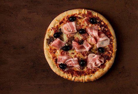 Pizza with prosciutto and mushrooms, bacon, olives, homemade, top view, no people