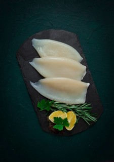 Fresh squid body, raw, three carcasses, top view, on black slate, no people