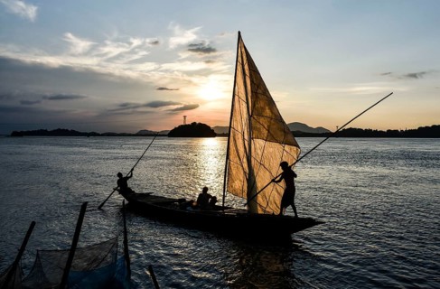 Fishermen paddle down the Brahmaputra River after fish in Guwahati, Assam, India on August 25, 2019