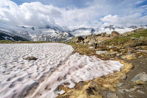 Mountaineers on hiking trail in picturesque mountain landscape, mountain peaks with snow and
