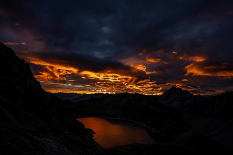 Lake Lüner See with Montafon mountains and dramatic cloudy sky at sunrise, Tschagguns, Rätikon,