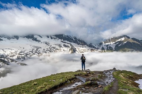 Mountaineer in front of mountain landscape with high fog in the valley, summit Hochfeiler and