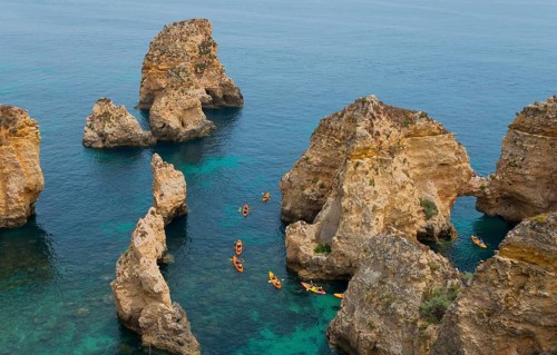 Kayakers explore the steep cliffs and coastline on the clear blue sea, Ponta da Piedade, point of