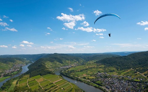 Paraglider flies high above the river with a wide view over the landscape, Paragliding, Bremm,