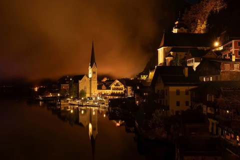 View of Hallstatt with the church and Lake Hallstatt at night. Clouds move through Hallstatt.