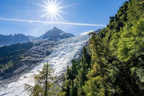 View of glacier Glacier des Bossons with sun star, behind summit of Aiguille du Midi, Chamonix,