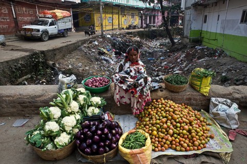 Vegetable seller in a street at Bodhgaya, India. Sewer is visible behind the woman