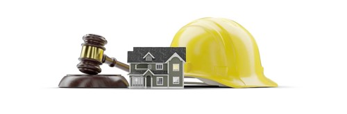 Miniature model house, yellow hard hat and gavel isolated on a white background