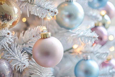 Close up of beautiful pastel colored bauble ornaments on branches of white christmas tree.