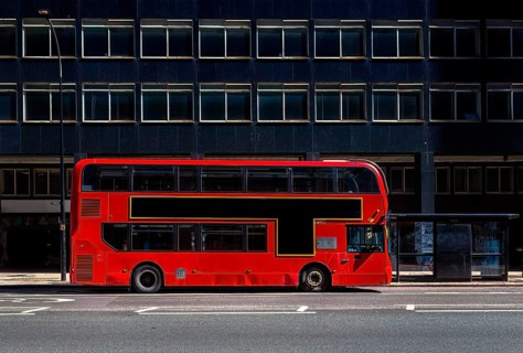 Red double-decker bus on a city street with free advertising space or advertising banner in front