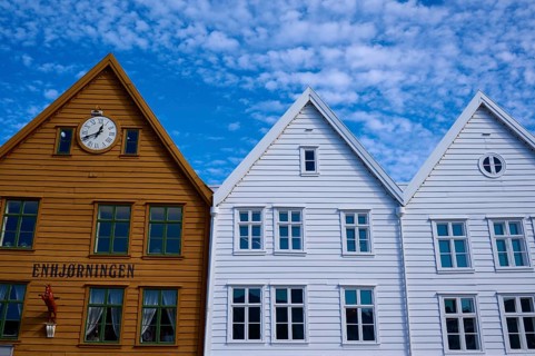 Traditional wooden houses under a blue sky with pitched roofs and multiple windows in a sunny old