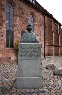 Wilhelm Löhe monument, bronze bust on a high granite stone plinth with three bronze reliefs, by
