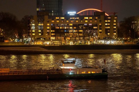 The Hyatt Regency Hotel on the Rhine, in Cologne Deutz, behind it the illuminated arch of the