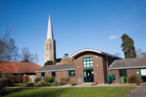 The octagonal tower of All Saints church, Wickham Market, Suffolk, England with public library and